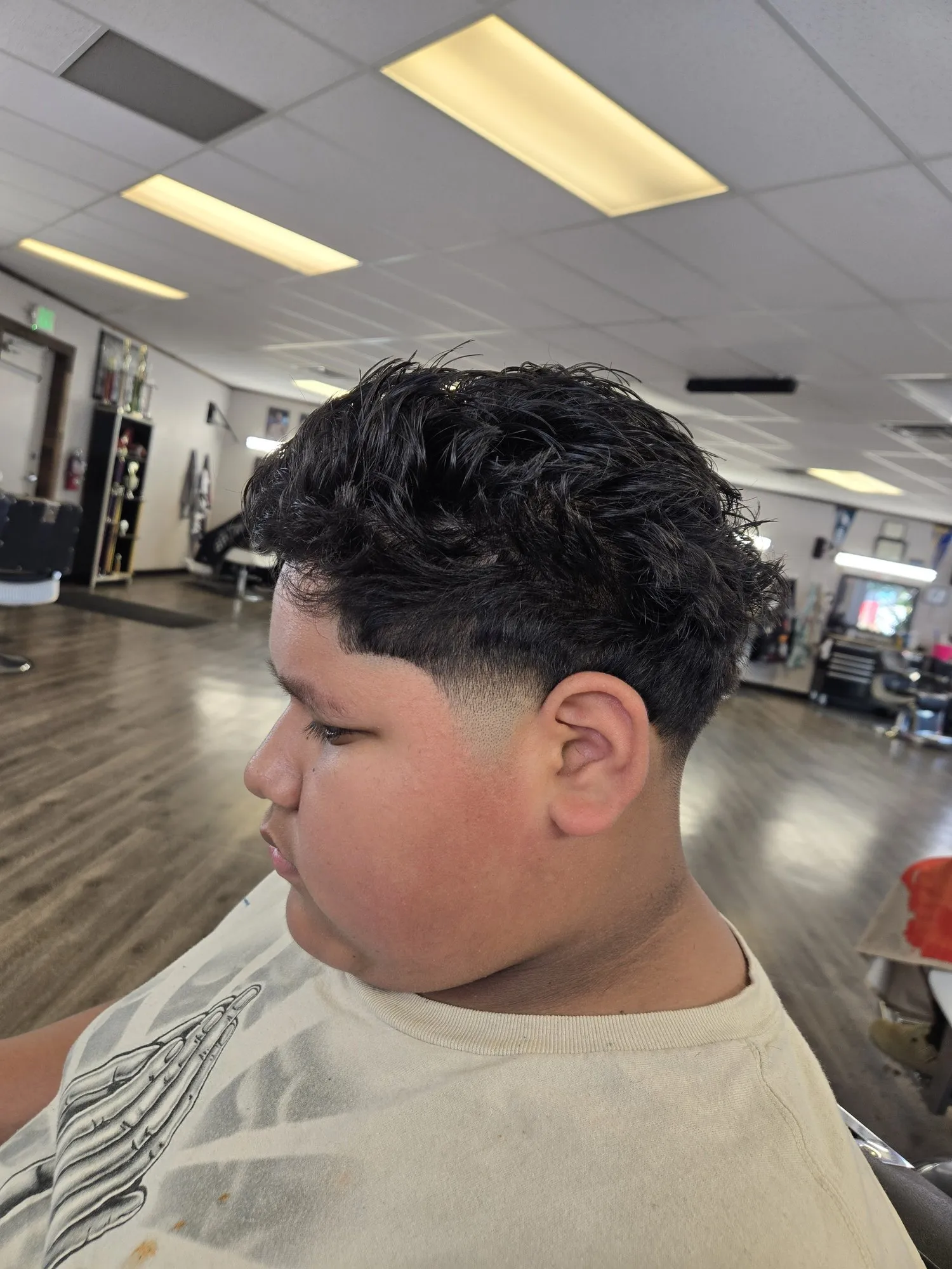 Side profile of a client after a cut by Bo: a textured dark top over a low taper.